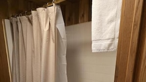 A bathroom with a shower curtain, a toilet, and a bathtub. - Hilltop Motel (Montello)
