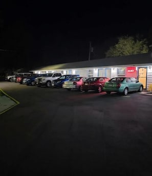 A parking lot with several cars parked in front of a building with a 'MONEY' sign.