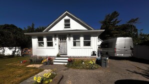 A white house with a front porch, a driveway, and a parked van.