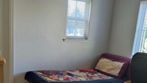 A small bedroom with a bed, a window, and a desk.