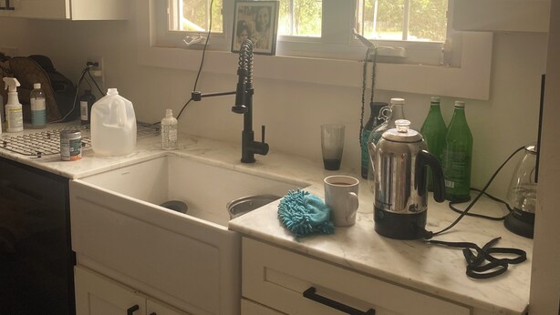 A kitchen with white cabinets, a sink, a window with a view, and various kitchen items on the counter.