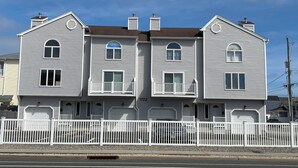 En tvåvånings bostadsbyggnad med vit fasad, många fönster och ett vitt staket framför.