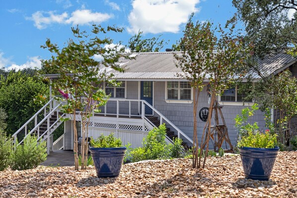A house with a porch, a staircase, and a flag. - New! Cozy home, Game Room + Covered Porch (Austin)