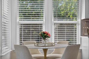A dining area with a round table, four chairs, and a vase of flowers. - New! Cozy home, Game Room + Covered Porch (Austin)