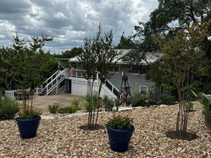 A residential area with a staircase leading to a house, surrounded by trees and potted plants. - New! Cozy home, Game Room + Covered Porch (Austin)