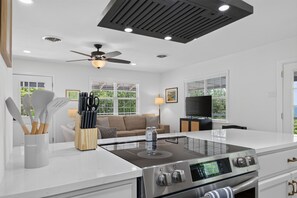 Eine moderne Küche mit einer zentralen Kochinsel, einem eingebauten Backofen und einem Deckenventilator.