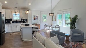 A modern kitchen with white cabinets, a central island, and pendant lighting. - Water Views and Great Location - BRAND NEW - 3 bedroom 3 bath soundside cottage (Kill Devil Hills)