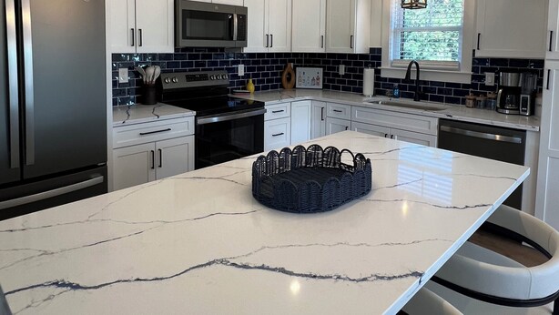 A modern kitchen with white cabinets, a large island, stainless steel appliances, and pendant lighting. - Water Views and Great Location - BRAND NEW - 3 bedroom 3 bath soundside cottage (Kill Devil Hills)