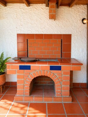 A brick-built outdoor oven with a tiled countertop, a potted plant, and a wooden ceiling structure. - Authentic Casa Paisa with a Private Patio and Outdoor Kitchen in Medellín (Medellín)