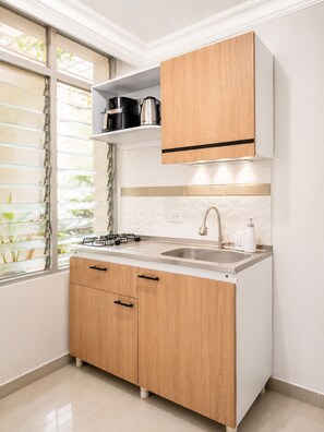 A modern kitchen with a gas stove, sink, wooden cabinets, and a window with blinds. - Authentic Casa Paisa with a Private Patio and Outdoor Kitchen in Medellín (Medellín)
