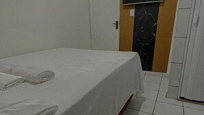 Una habitación de hotel con una cama, un televisor instalado en la pared y una puerta que da a un baño.