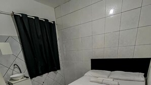 Une chambre à coucher avec un lit, une table de chevet, un lavabo et un miroir.
