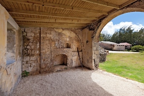 Ein Gebäude aus Stein mit einem rundbogenförmigen Eingang, Holzbalkendecke und Kiesboden.