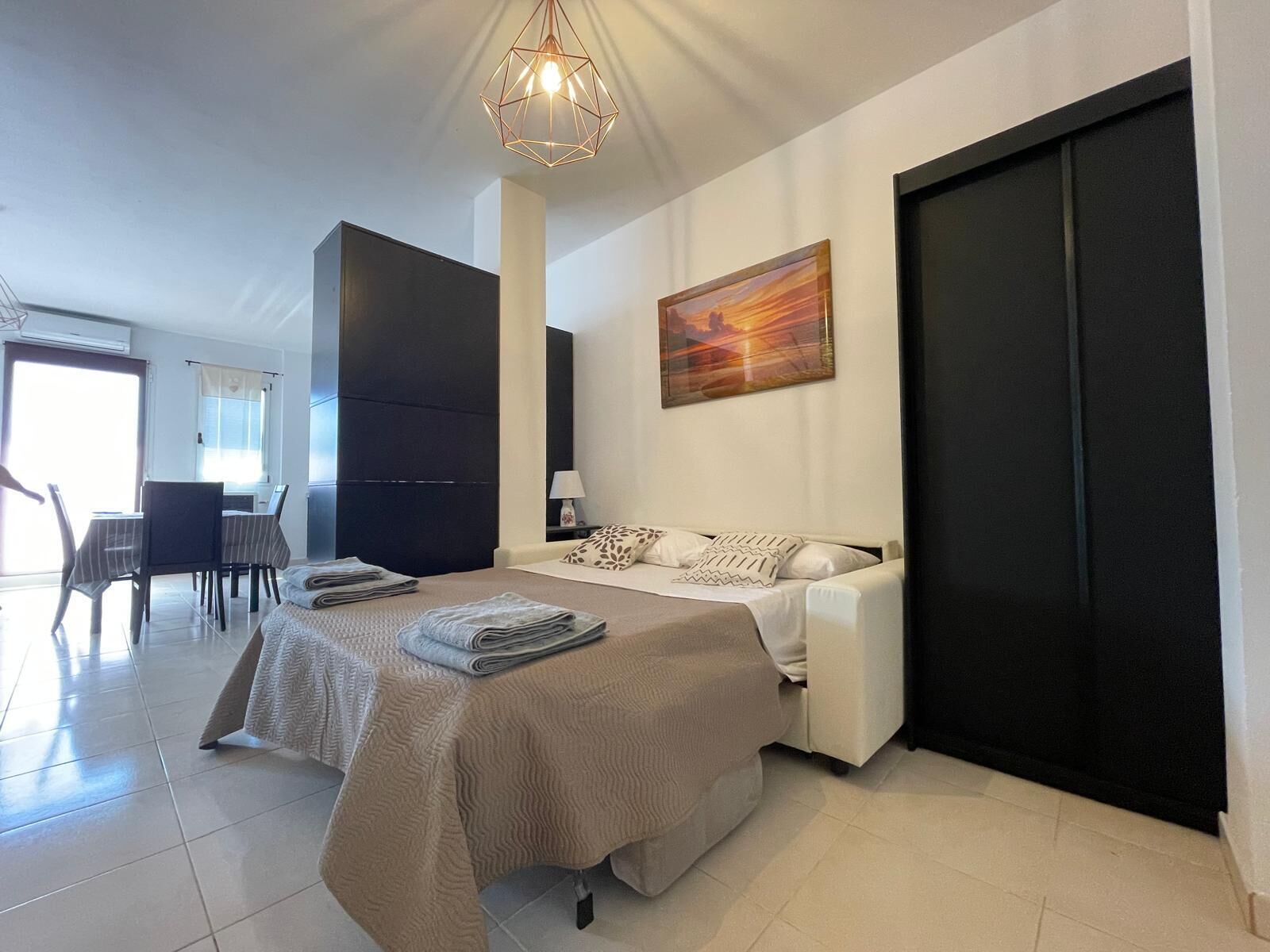 Ein modernes Schlafzimmer mit Bett, Nachttisch und einem Bild an der Wand.