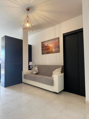 A modern living room with a sofa, a pendant light, a painting, and a closed door. - Casa Lily is a cozy house in the hills with a view of the sea. (Monade Santa Lucia)
