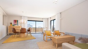Una sala de estar moderna con comedor, ventanas amplias y vista al mar.