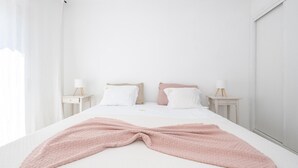 Un dormitorio minimalista con una cama grande, dos mesitas de noche y vistas al exterior.