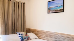 Una habitación de hotel con cama, cortinas, un cuadro y un cabecero de madera.