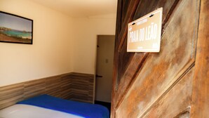 Habitación de hotel con una cama, una puerta de madera y un cartel que dice 'Praia do Leão'.