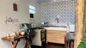 Una cocina con estufa, lavamanos y mesa de madera con frascos.