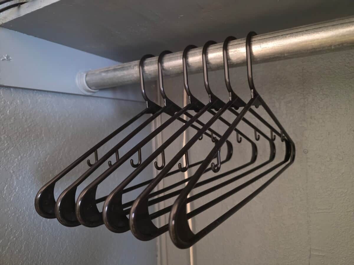 A metal rack with multiple hooks against a wall.