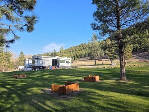 Un véhicule récréatif (VR) se trouve dans une zone herbeuse, avec des arbres et une colline en arrière-plan.