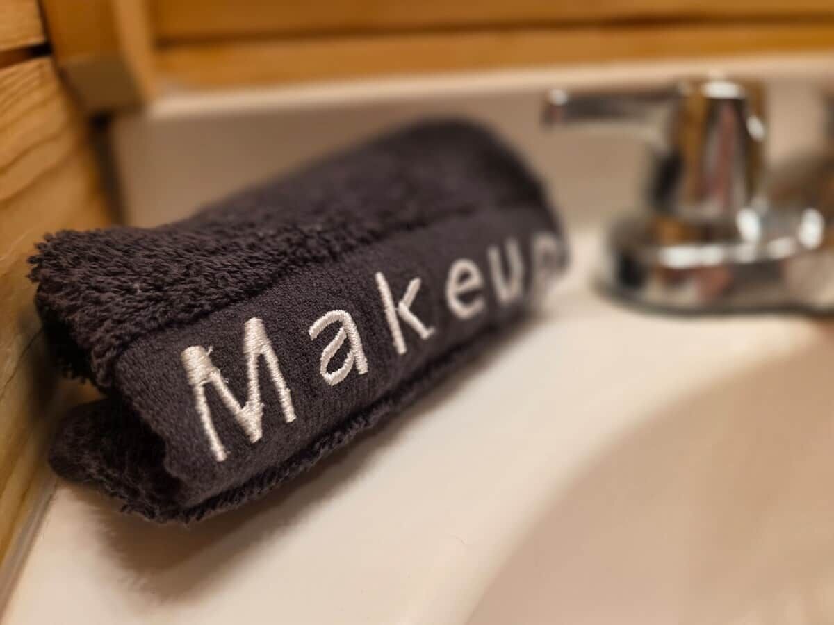 Et håndklæde med ordet 'Makeup' på en vask i et badeværelse.