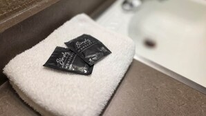 Ein weißes Handtuch auf einer Badezimmerablage mit zwei schwarzen Packungen mit dem Aufdruck 'Simply Wonder'.