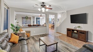 Uma sala de estar moderna com sofás de couro, uma mesa de centro de madeira e uma TV grande.