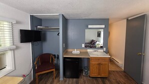 A compact room with a bed, a desk, a chair, a TV, a sink, and a mirror. - 7R Guest Ranch - Room 12 (Pet Friendly) (Lewis and Clark County)