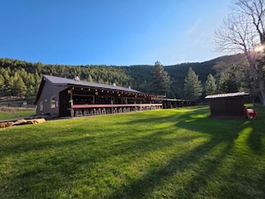 Ein großes Gebäude mit überdachtem Außenbereich, umgeben von einer grünen Wiese und Bäumen.