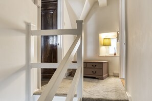 Eine Treppe führt zu einem Schlafzimmer mit einer Holztür, einer Nachttischlampe und einem Schminktisch.