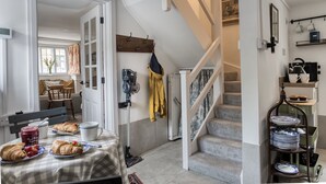 A dining area with a table set for breakfast, a staircase, and a kitchen area with shelves.