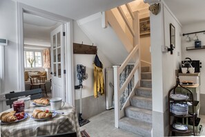 A dining area with a table set for breakfast, a staircase, and a kitchen area with shelves.