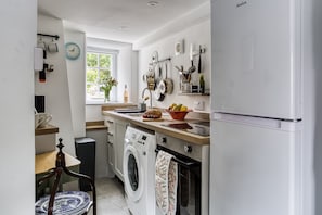Eine kleine Küche mit Waschmaschine, Spüle und Kühlschrank.