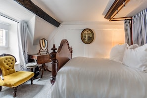 Ein Schlafzimmer mit Bett, Stuhl, Schreibtisch und Spiegel.
