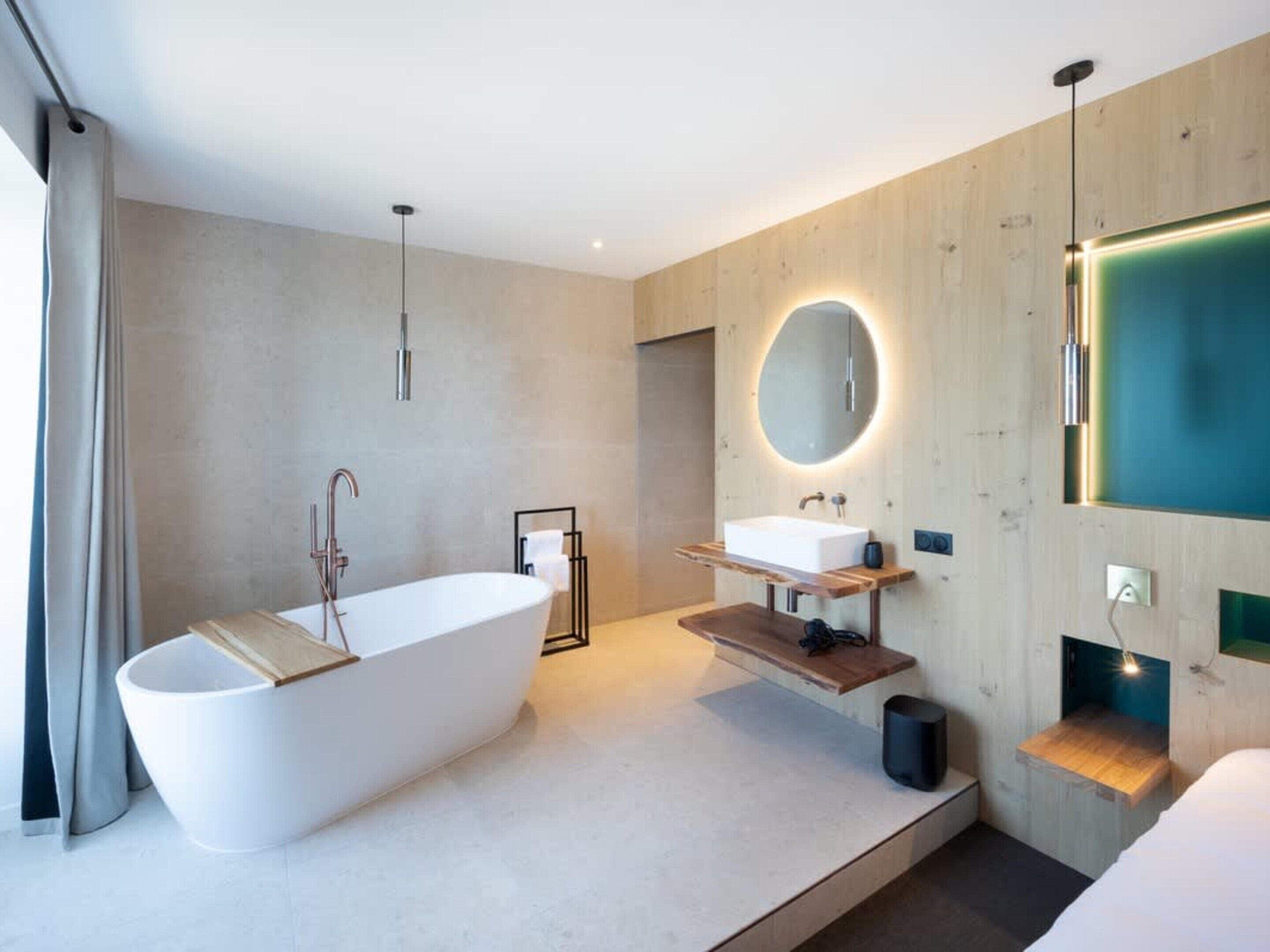 Un baño moderno con una bañera independiente, un tocador con espejo y un panel de pared de madera.