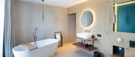 Un baño moderno con una bañera independiente, un tocador con espejo y un panel de pared de madera.