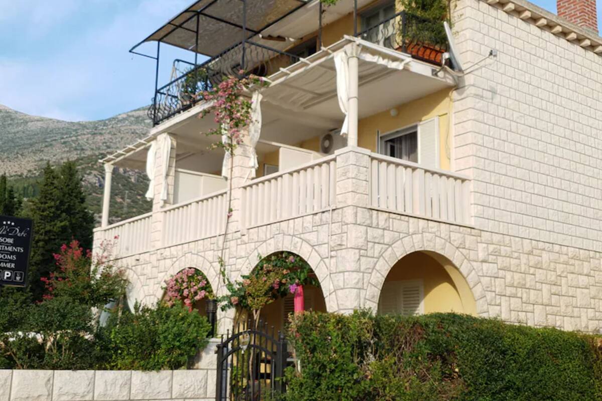 A stone building with a balcony, arched windows, and a sign indicating it is a hotel.