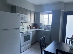 Eine Küche mit Kühlschrank, Mikrowelle, Backofen und Spüle.