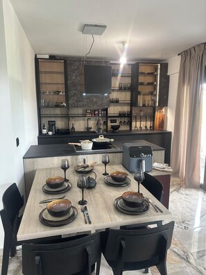 A modern kitchen with a dining area, equipped with a coffee maker, wine glasses, and a flat-screen TV. - Artion jacuzzi Villa Nikiti a 3-bedroom apartment with jaccuzi in charmingNikiti (Nikiti)