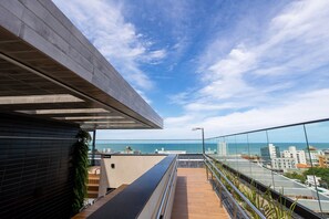 A modern building with a rooftop terrace, a glass railing, and a view of the sea. - AT Self #804 Steps From the Beach by Carpediem (João Pessoa)