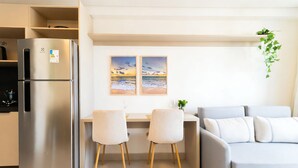 A modern kitchen with a stainless steel refrigerator, a dining area with two chairs, and a grey sofa. - AT Self #804 Steps From the Beach by Carpediem (João Pessoa)