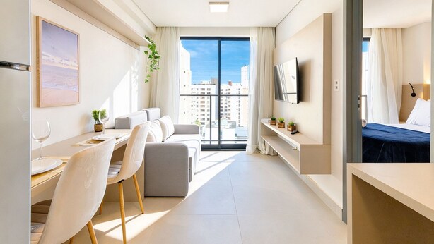 A modern hotel room with a dining area, a sofa, a TV, and a large window with a city view. - AT Self #804 Steps From the Beach by Carpediem (João Pessoa)
