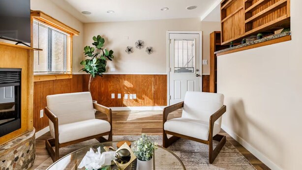 A living room with two white armchairs, a glass coffee table, a fireplace, wooden shelving, and a door with a window. - 3-bedroom Phoenix Cabin with cool AC for relaxing stay (Phoenix)