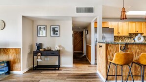 A modern kitchen with wooden cabinets, a stainless steel refrigerator, and a bar area with two stools. - 3-bedroom Phoenix Cabin with cool AC for relaxing stay (Phoenix)