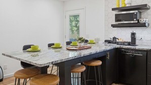 Une cuisine moderne dotée d’un plan de travail en marbre, de tabourets de bar, d’un coin café et d’un four à micro-ondes.
