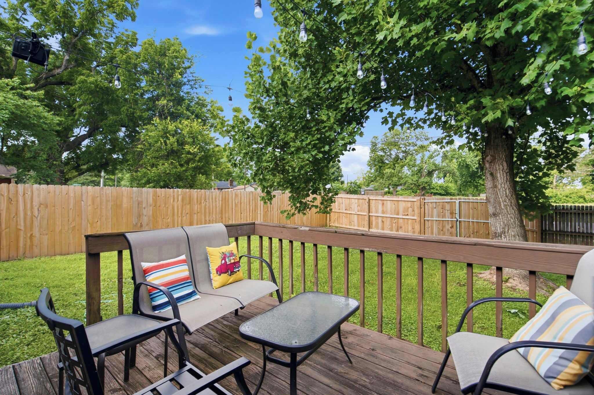 Una terraza de madera con muebles de exterior, como sillas y una mesa.
