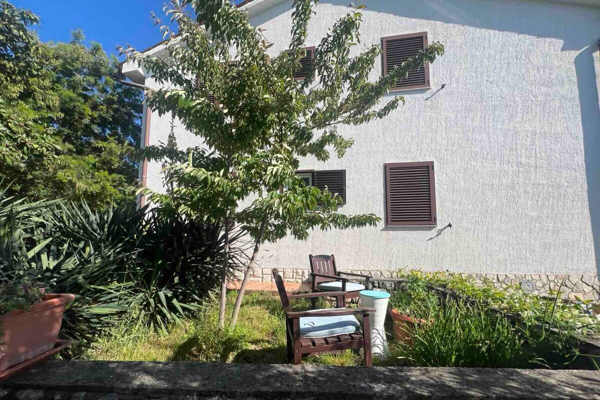 A building with a white exterior, multiple windows with shutters, and a patio area with outdoor furniture.