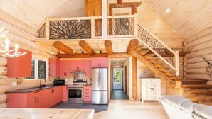 Ein rustikaler Innenraum einer Blockhütte mit Küche, Essbereich und einer Treppe.